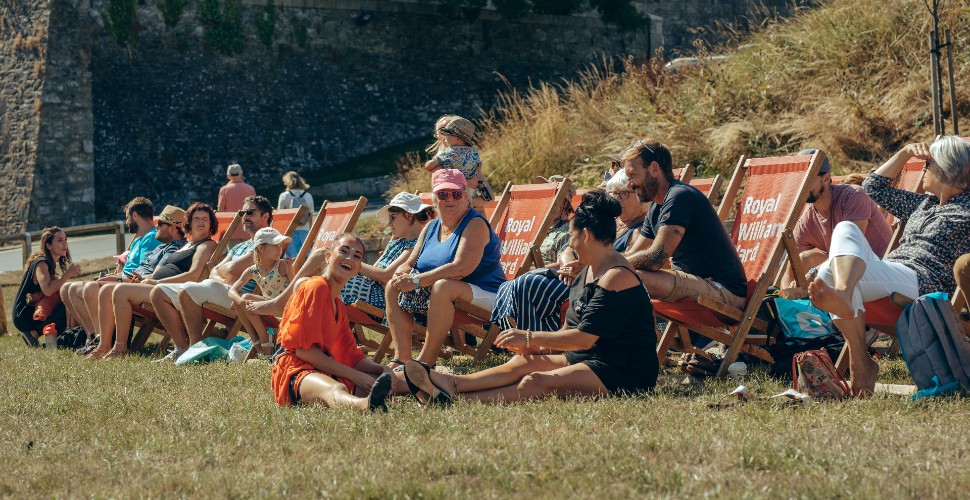 People sat in deckchairs on the green at Royal William Yard